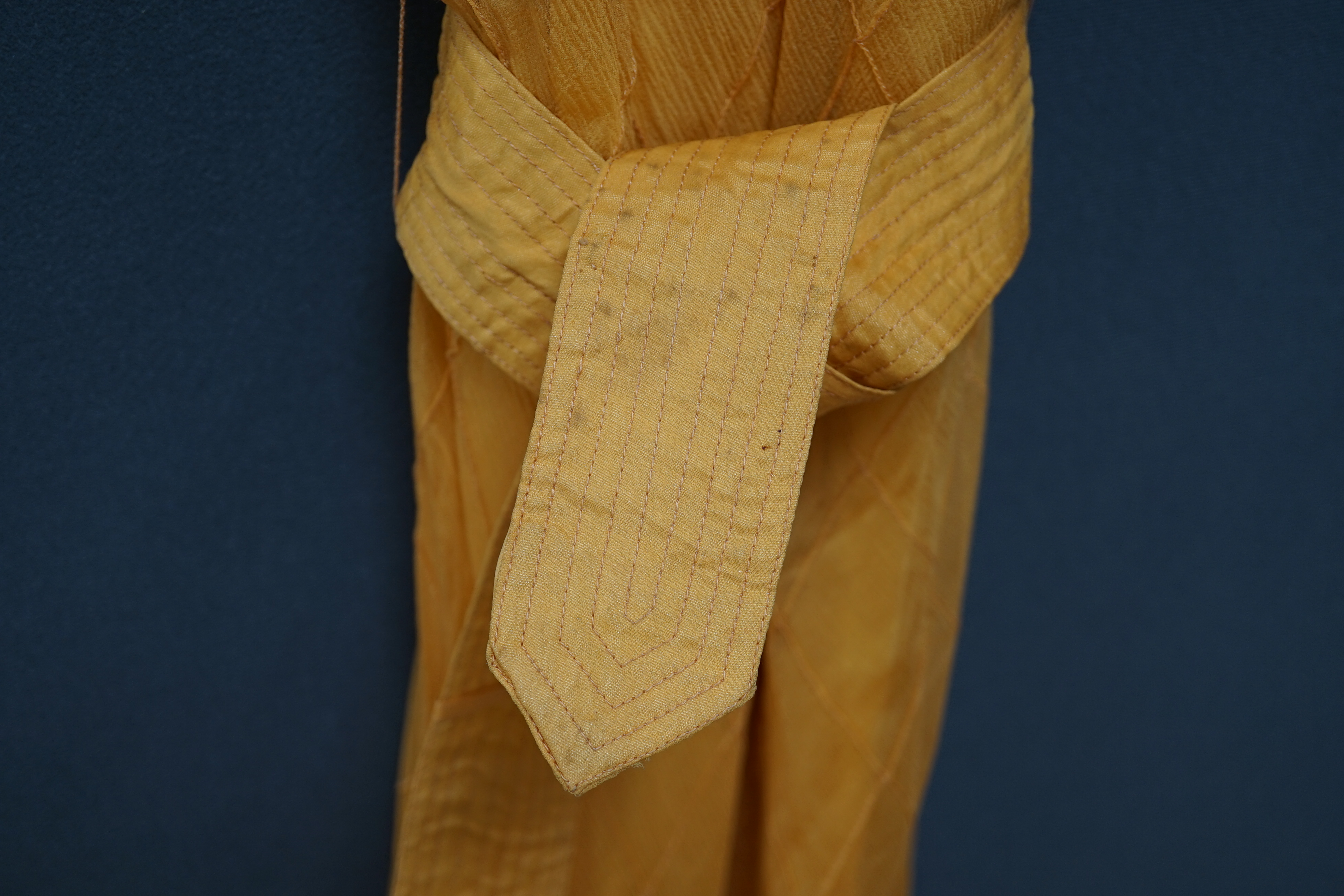 A 1930’s Harrods labelled saffron silk chiffon evening dress and jabot, lined in the same coloured taffeta, the dress kipper shaped with thin camisole straps and the chiffon sewn on the bias in diagonal seams finished wi